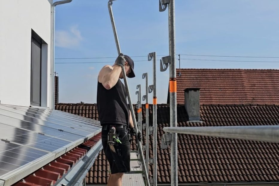 Gerüstbau Bauarbeiter auf einem Gerüst arbeitet an einem Gebäude mit Solarpanels.